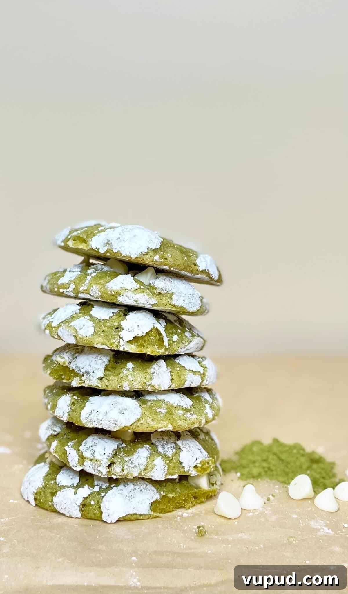 Matcha Crinkle Cookies Recipe: Soft, Chewy Green Tea Cookies 4 Tall stack of cookies on a table with matcha powder and white chocolate chips.