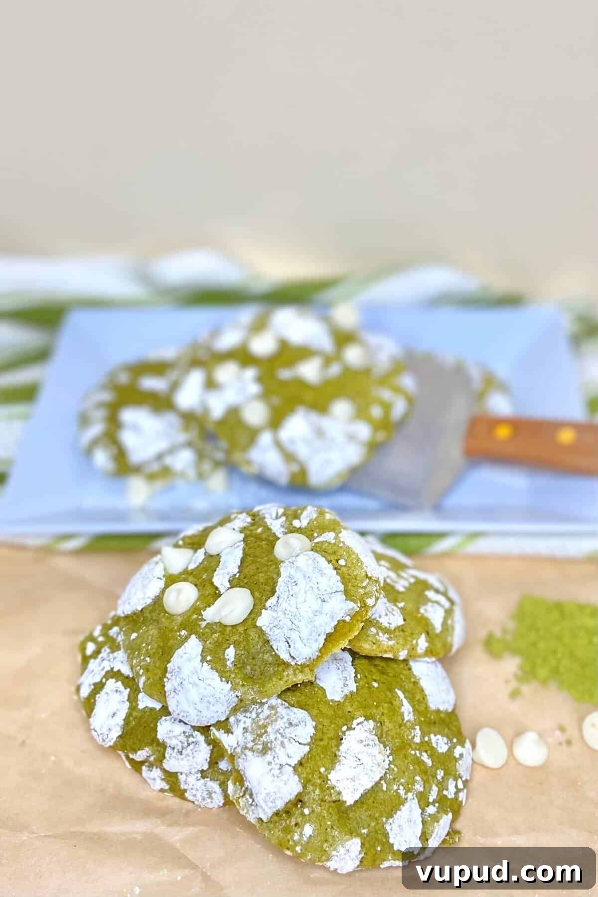 Matcha Crinkle Cookies Recipe: Soft, Chewy Green Tea Cookies 9 Cookies stacked on a table, with cookie sheet and spatula.