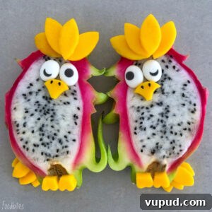 Parrot-Inspired Dragon Fruit Snacks: Tropical Treats for Birds 3 Two dragon fruit halves decorated with mango and other fruit pieces to resemble parrots.