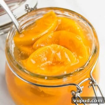 Easy Homemade Peach Pie Filling in Glass Jar on White Marble Background.