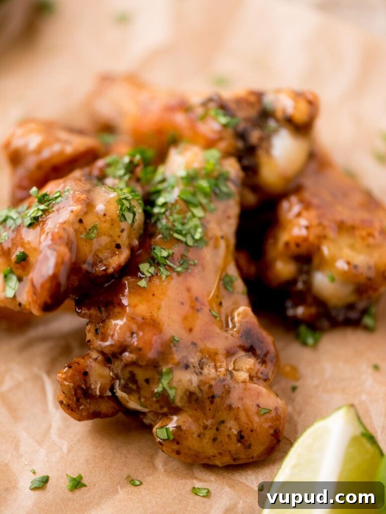 Tequila-Lime Chicken Wings: Zesty Grilled Wing Recipe 10 Tequila lime glazed chicken wings with chopped cilantro served on parchment paper with a lime wedge.