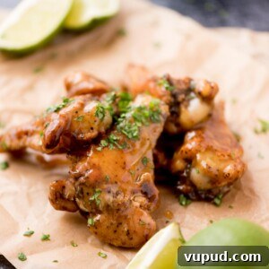 Tequila-Lime Chicken Wings: Zesty Grilled Wing Recipe 12 Close up of tequila lime wings with chopped cilantro garnished on top laying on parchment paper.