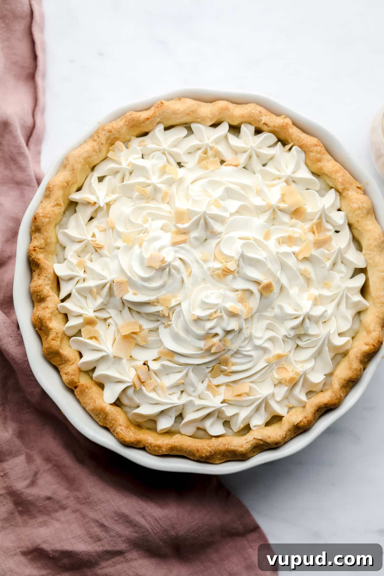 Creamy Vegan Coconut Cream Pie Recipe for Perfect Dessert 6 baked vegan coconut cream pie with whipped cream and toasted coconut shreds on top.