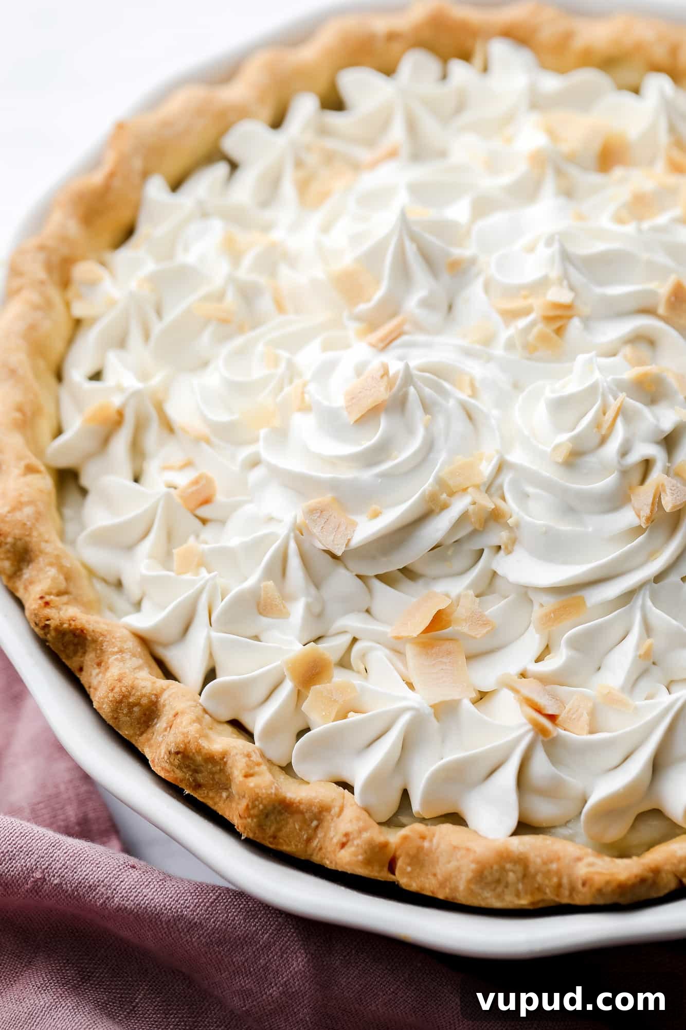 Creamy Vegan Coconut Cream Pie Recipe for Perfect Dessert 7 close up on a vegan coconut cream pie with whipped cream and coconut shreds on top.