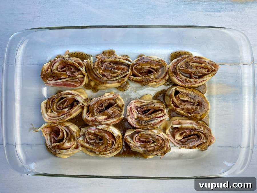 Quick Ham and Cheese Roll-Ups: 4-Ingredient Party Snack 15 Ham and cheese roll-ups in baking dish with glazed on top