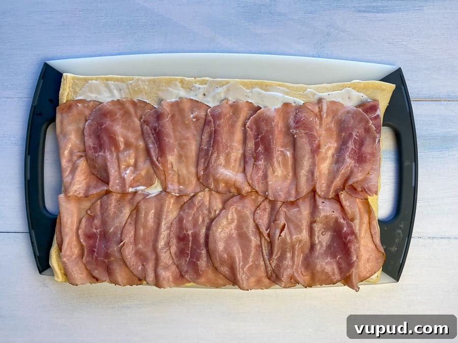 Quick Ham and Cheese Roll-Ups: 4-Ingredient Party Snack 7 Crescent dough on cutting board with ranch dressing and layer of ham lunchmeat