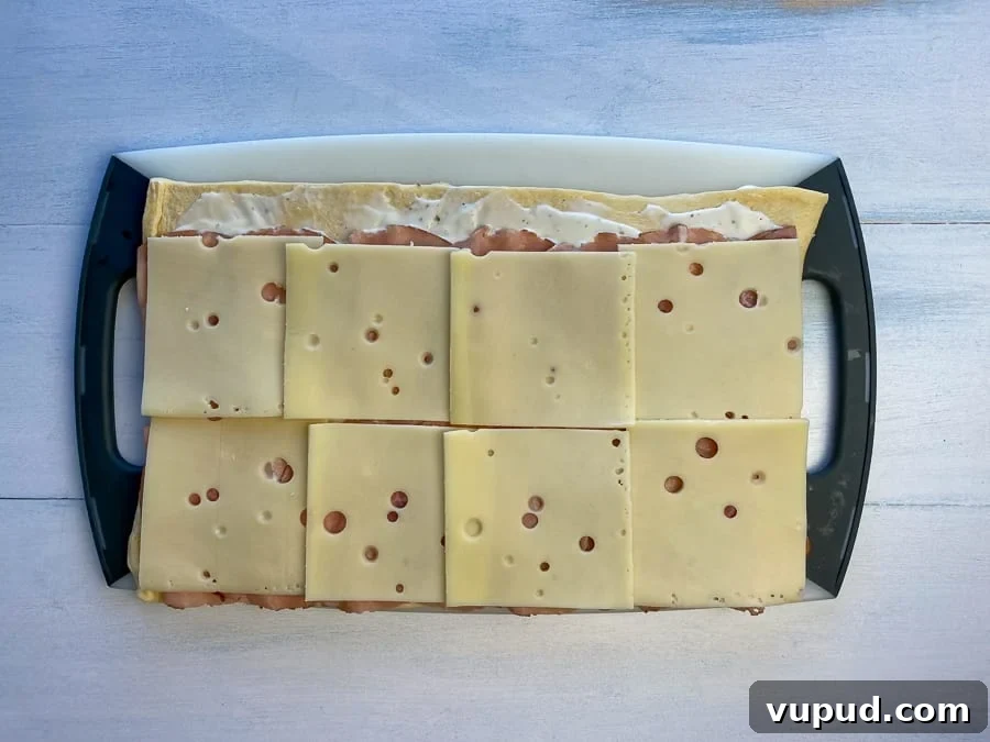 Quick Ham and Cheese Roll-Ups: 4-Ingredient Party Snack 8 Layer of sliced Swiss cheese added on top of ham roll-up