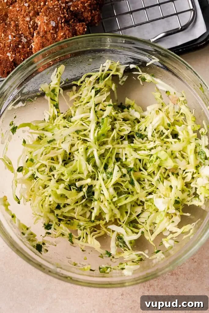 What is schnitzel A bowl of fresh, shredded cabbage slaw with parsley, ready to be served alongside the schnitzel.
