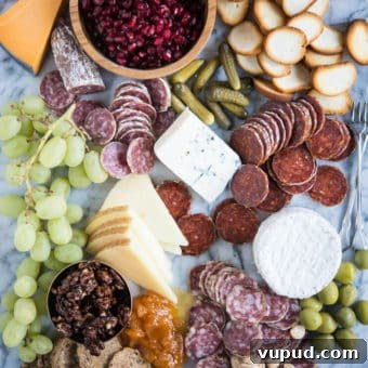 Perfect Charcuterie Board Guide: Build an Elegant Spread for Any Occasion 5 Charcuterie board with meats, cheeses, honey, nuts, a wooden bowl of pomegranates, olives, grapes, pickles, crackers, on a marble board