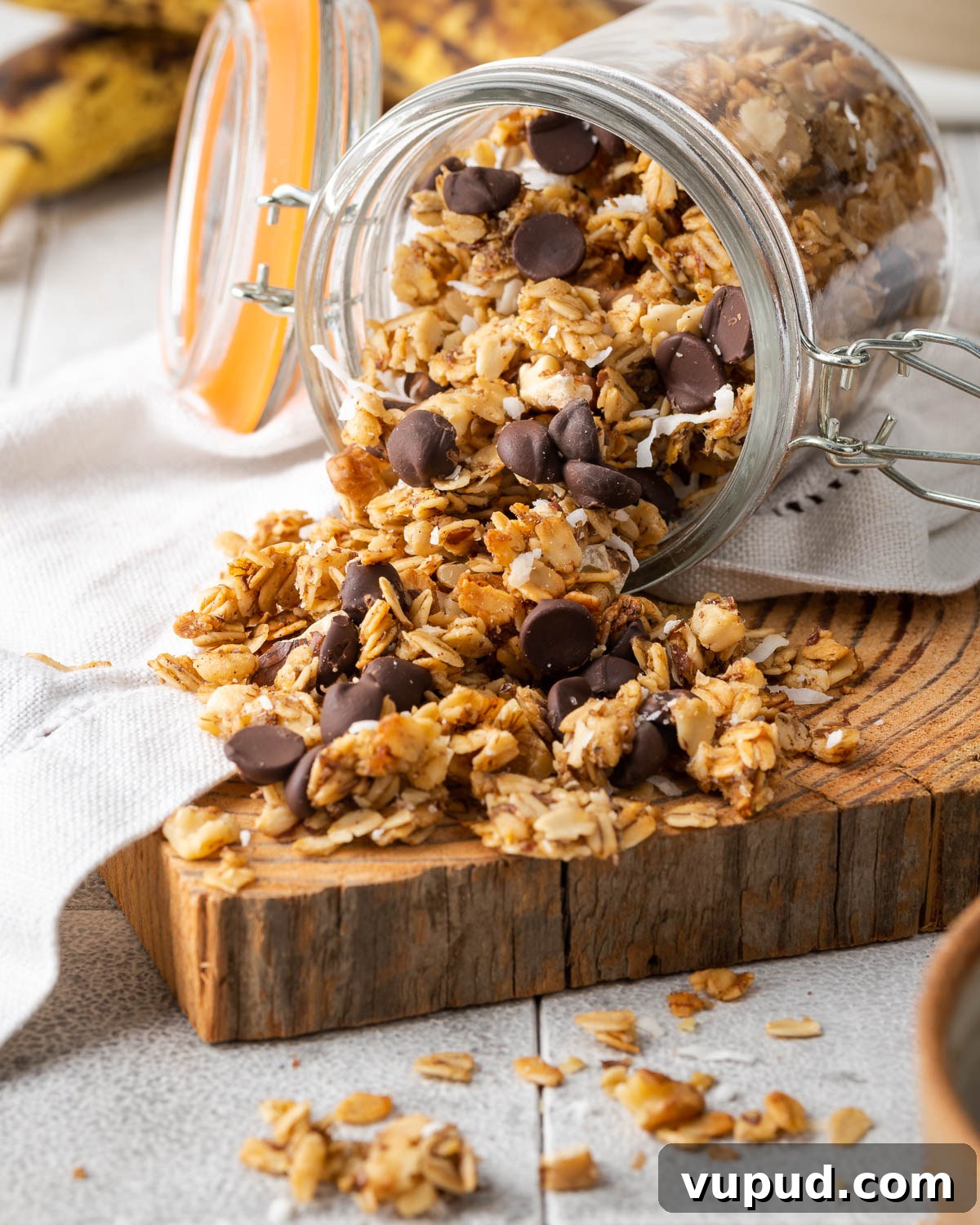 Homemade Chocolate Banana Granola Recipe for Crunchy Breakfast 2 A jar of chocolate banana granola spilled on a wooden cutting board.