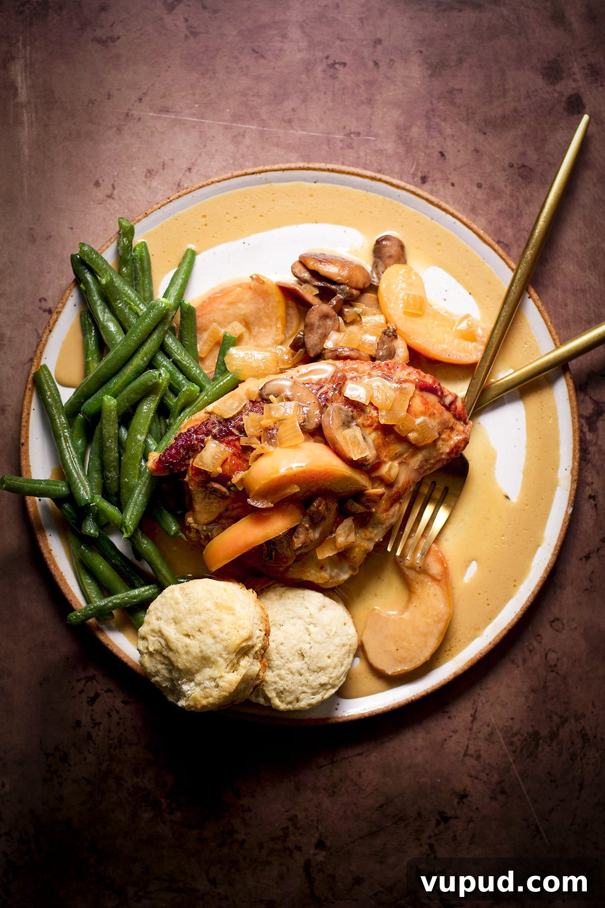Chicken, Apples & Mushrooms in Cider Cream Sauce 2 A serving of chicken and apples with cider cream sauce and green beans on a dinner plate.
