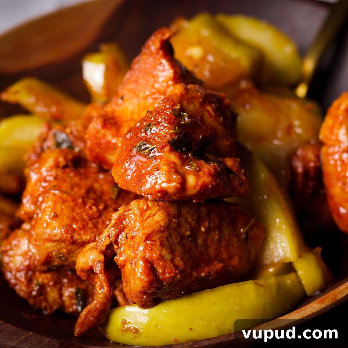 A wood bowl filled with Spanish pork bites and brown sugar and butter fried apples.