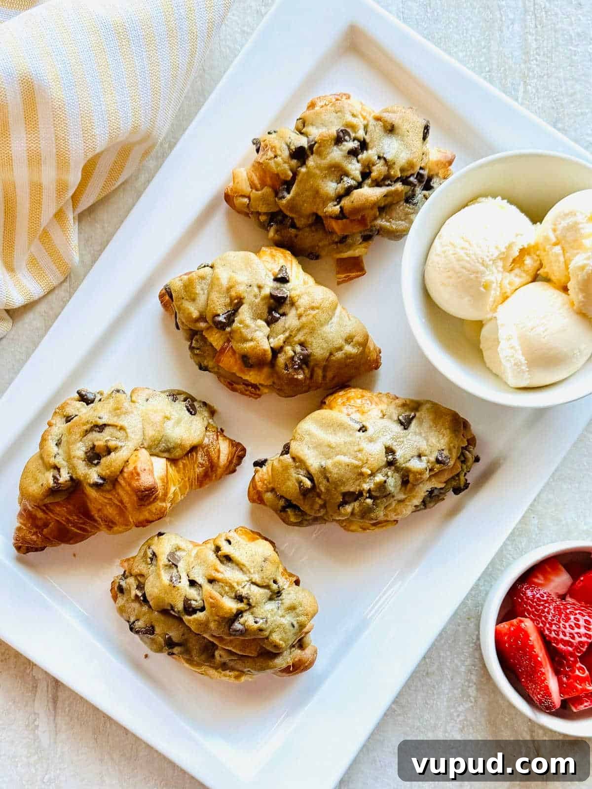How to Make a Crookie: Viral Croissant Cookie Recipe from TikTok 2 viral tiktok crookie croissant stuffed with cookie sitting next to a bowl of ice cream and strawberries.
