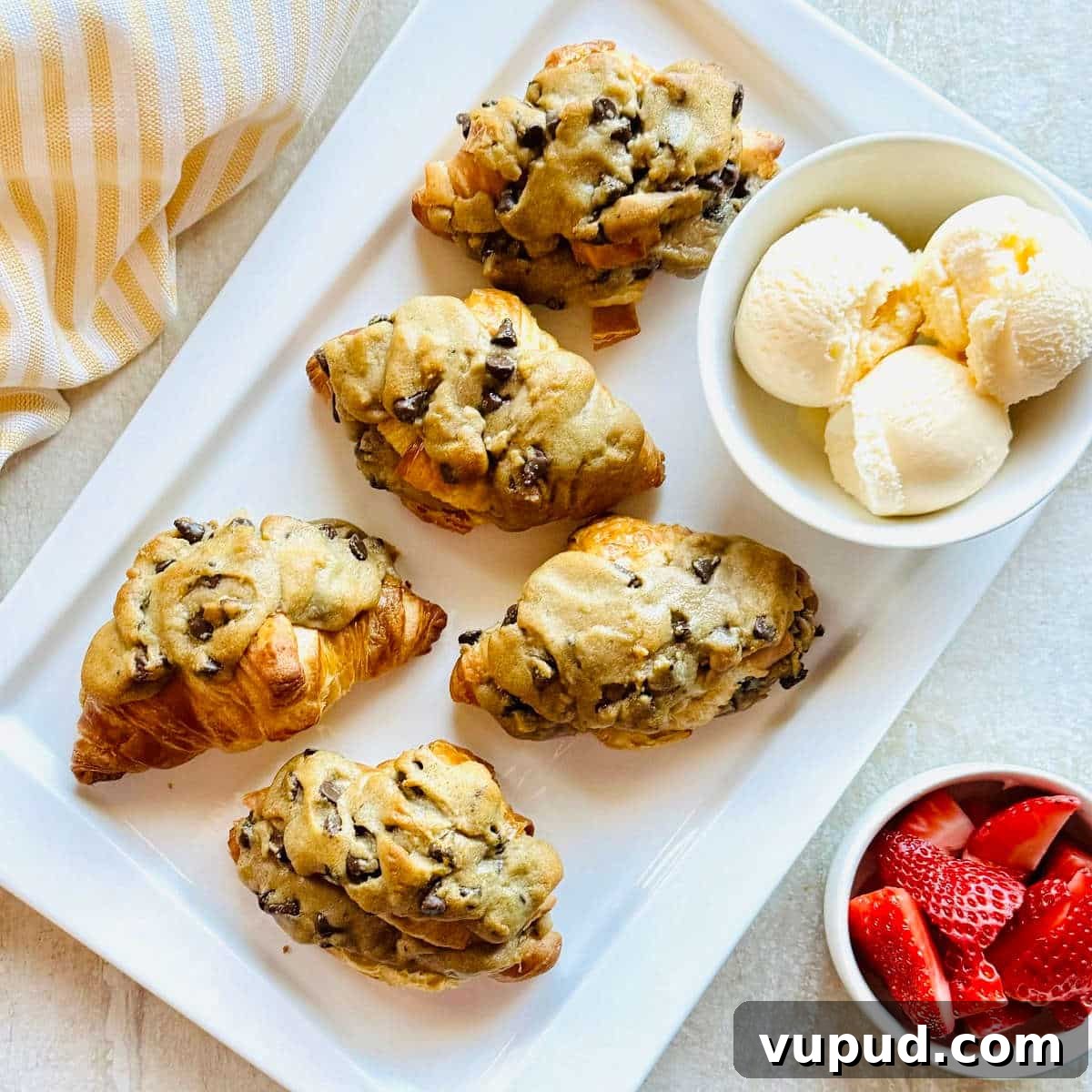 How to Make a Crookie: Viral Croissant Cookie Recipe from TikTok 3 crookie croissant stuffed with cookie on a plate with a bowl of ice cream.