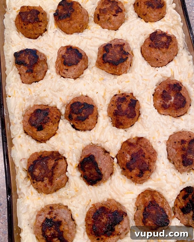Cheesy Meatball and Hash Brown Casserole Recipe 8 Meatballs pressed into potato mixture in baking dish.