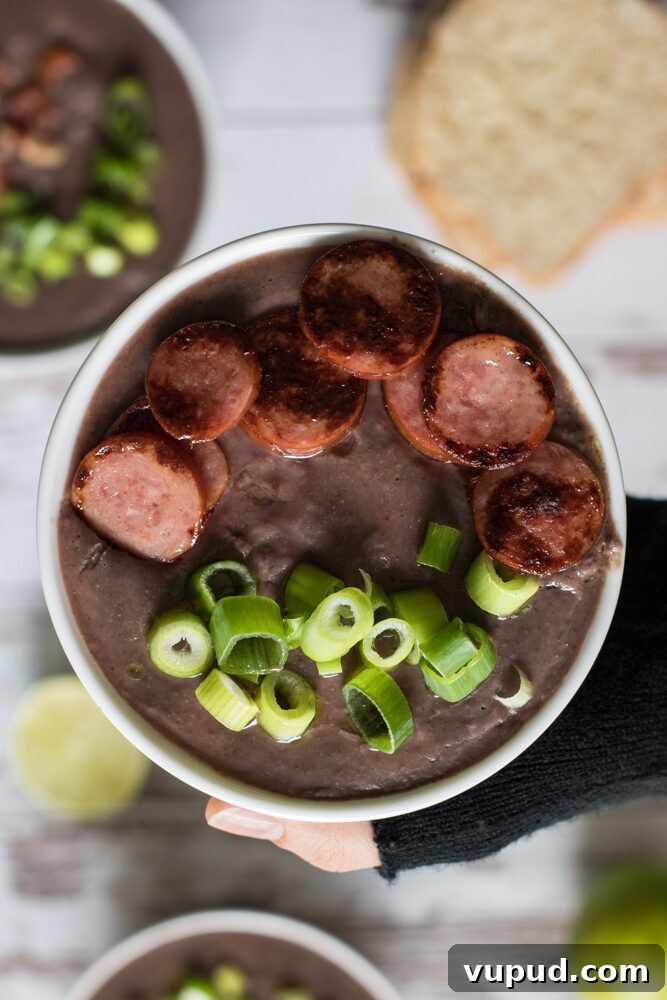 Hand holding a bowl of Bacon black bean soup.