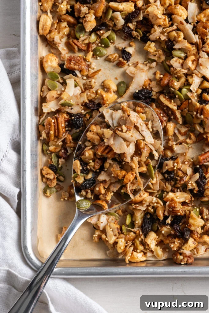 Grain-Free Homemade Granola Recipe for Crunchy, Low-Carb Mornings 2 silver spoon on the bottom left corner of a parchment lined baking sheet scooping up some healthy grain free granola.