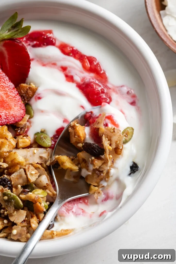Grain-Free Homemade Granola Recipe for Crunchy, Low-Carb Mornings 13 closeup shot of a white bowl filled with yogurt topped with grain free granola, fresh strawberries, and strawberry chia jam.