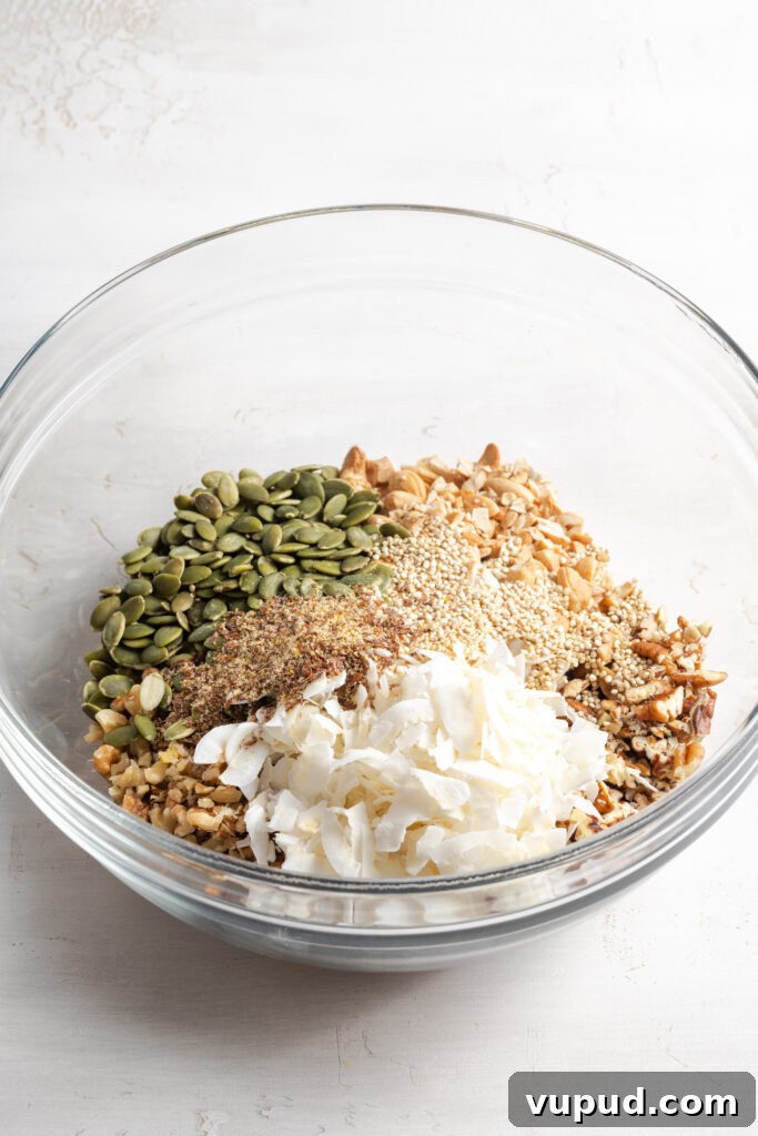 Grain-Free Homemade Granola Recipe for Crunchy, Low-Carb Mornings 7 dry oat-free granola ingredients added to a mixing bowl before mixing.