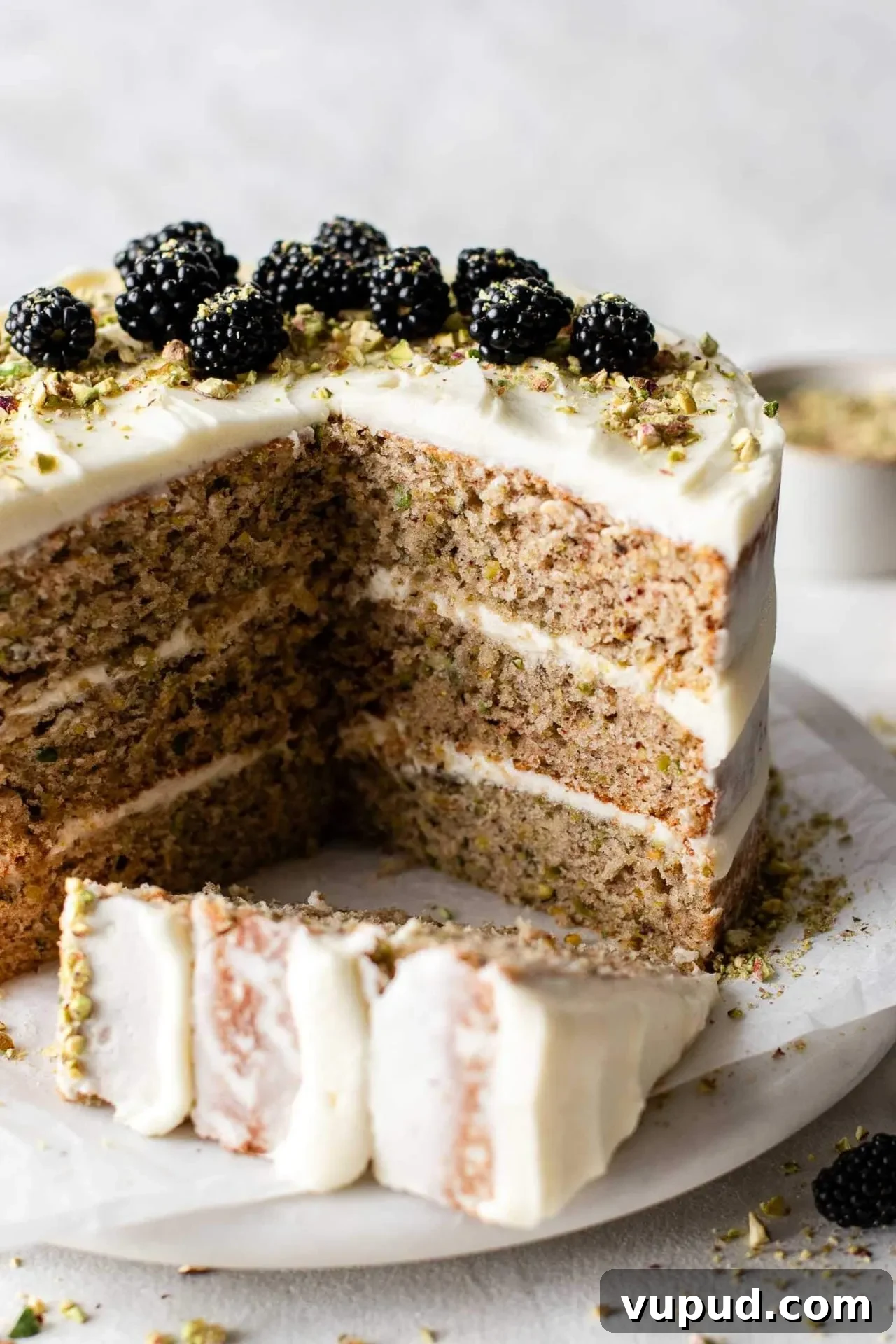 Silky Pistachio Layer Cake with Toasted Nut Crumble 2 sliced pistachio cake on cake plate