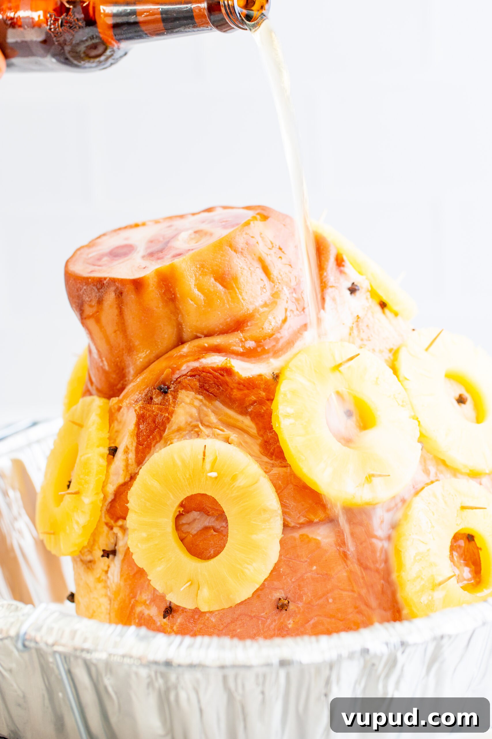 Glazed Pineapple Baked Ham Recipe for Holiday Dinner 6 pouring the beer over top of the assembled ham.