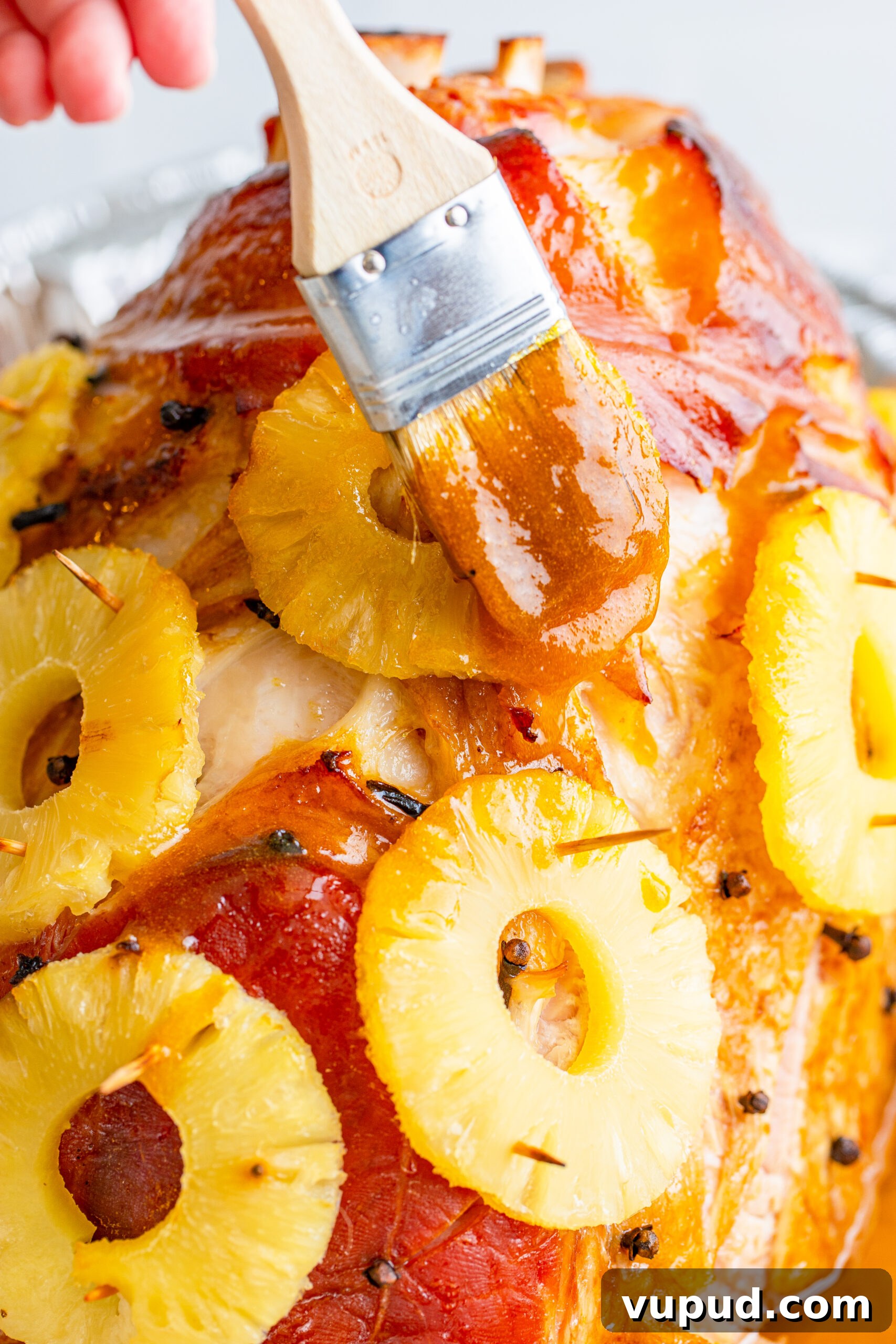Glazed Pineapple Baked Ham Recipe for Holiday Dinner 9 Brushing glaze on the ham using a wooden brush.