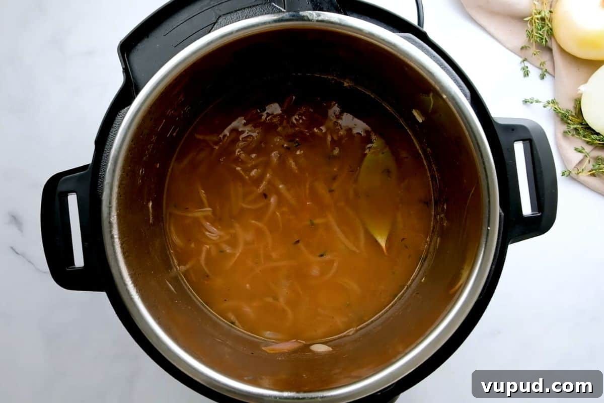 How to Make French Onion Soup in Instant Pot. Onions, broth and seasonings layered in inner pot for French Onion Soup before pressure cooking.