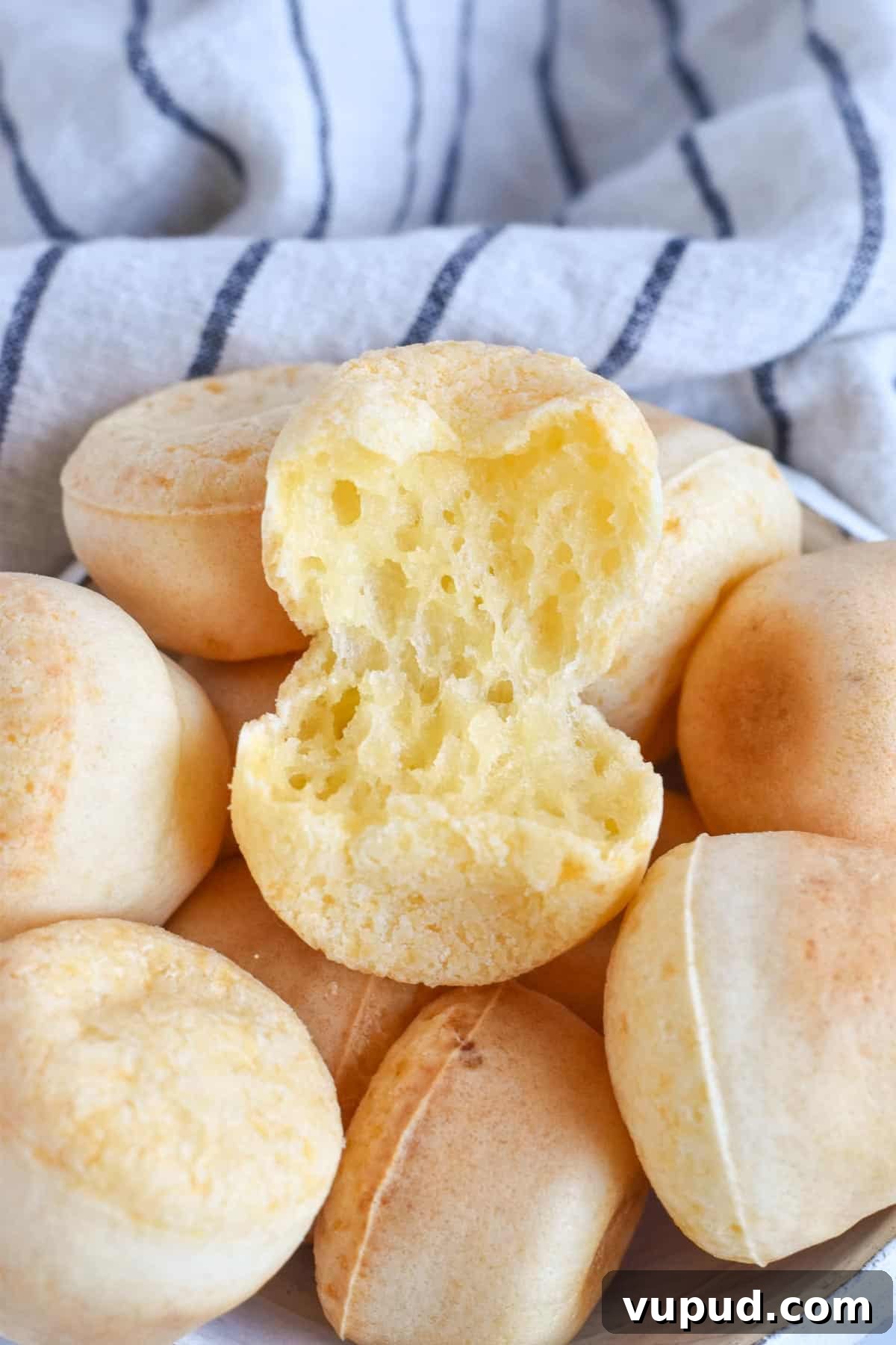 Fogo de Chão Pão de Queijo Recipe: How to Make Authentic Cheese Bread 2 cheese bread ripped open on pile of rolls.
