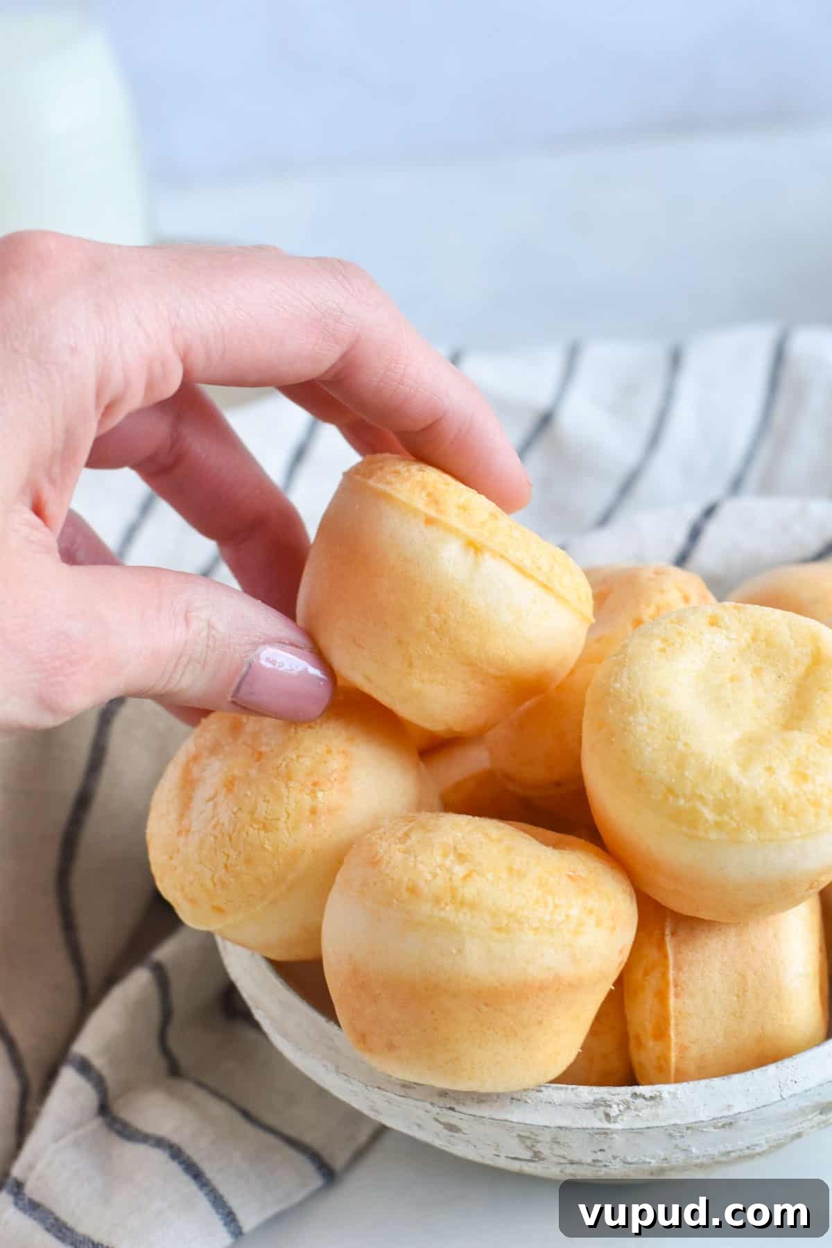 Fogo de Chão Pão de Queijo Recipe: How to Make Authentic Cheese Bread 8 hand grabbing fogo de chao bread out of a bowl.