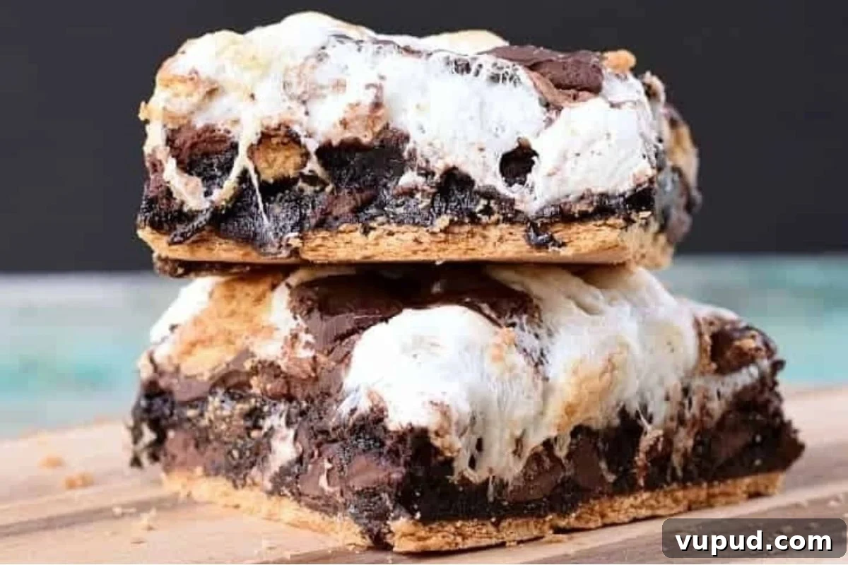 24 Irresistible S'mores Recipes to Enjoy All Year Long 13 A stack of s'mores bars, resembling brownies, on a cutting board.