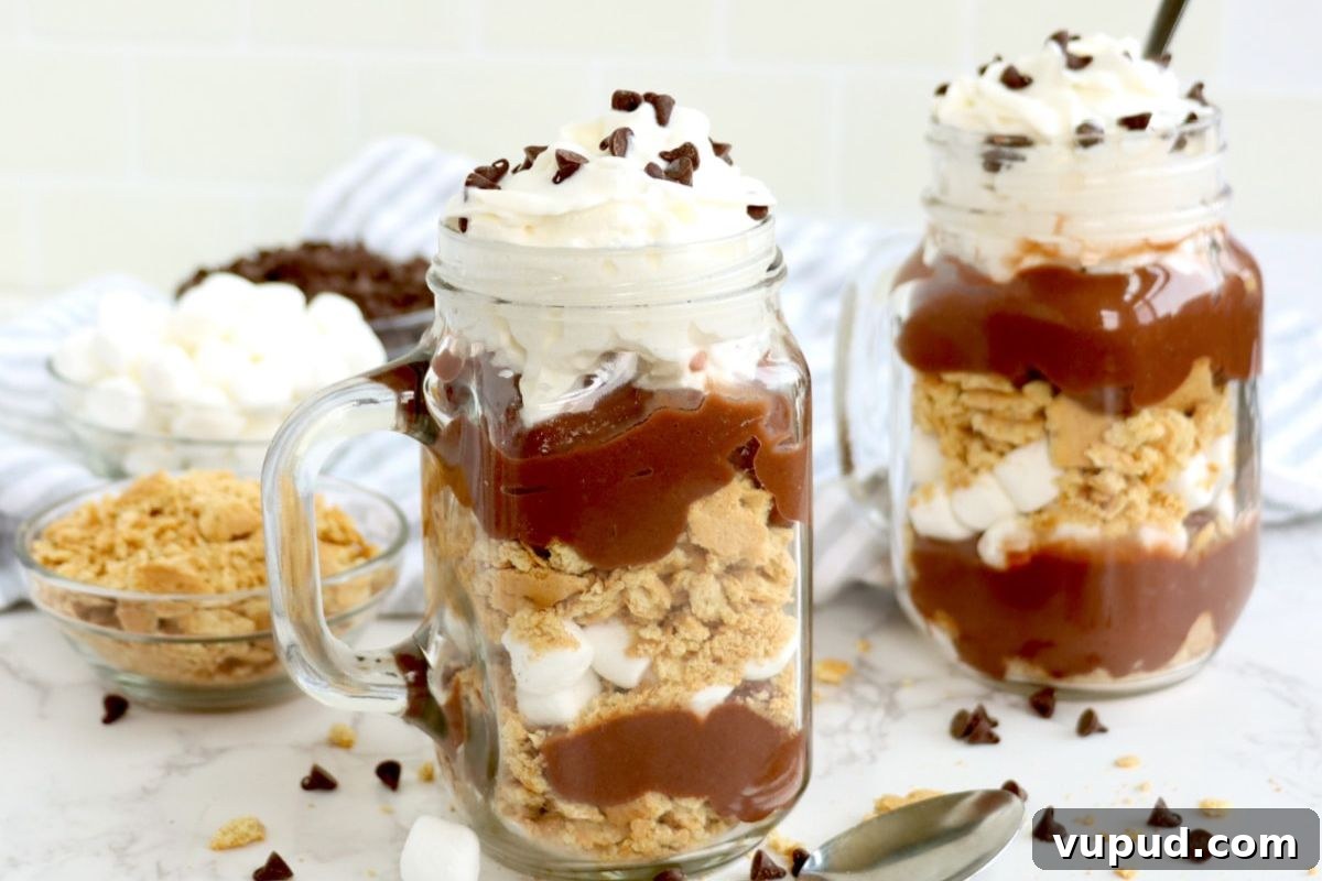 24 Irresistible S'mores Recipes to Enjoy All Year Long 4 Two jars of layered s'mores dessert with whipped cream topping, sprinkled with chocolate chips and cookie crumbs.