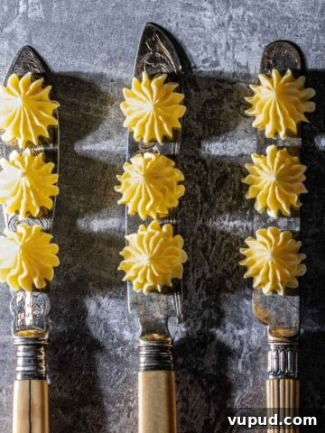 Three knifes with three butter rosettes on each blade.