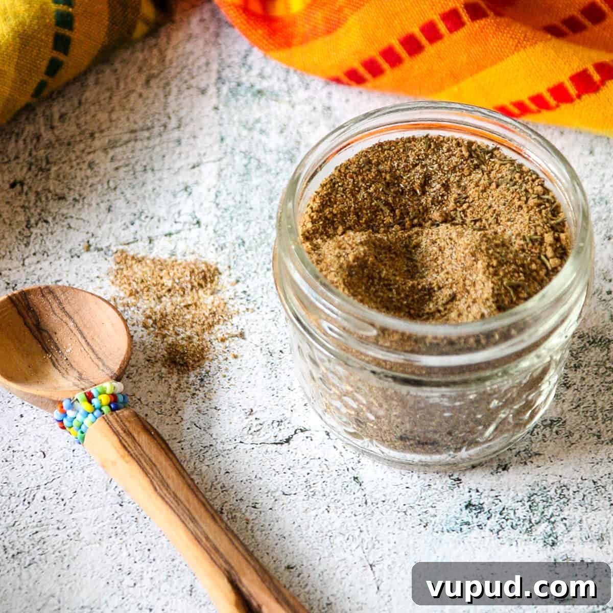 Jamaican jerk seasoning blend in a glass jar on a marble countertop.