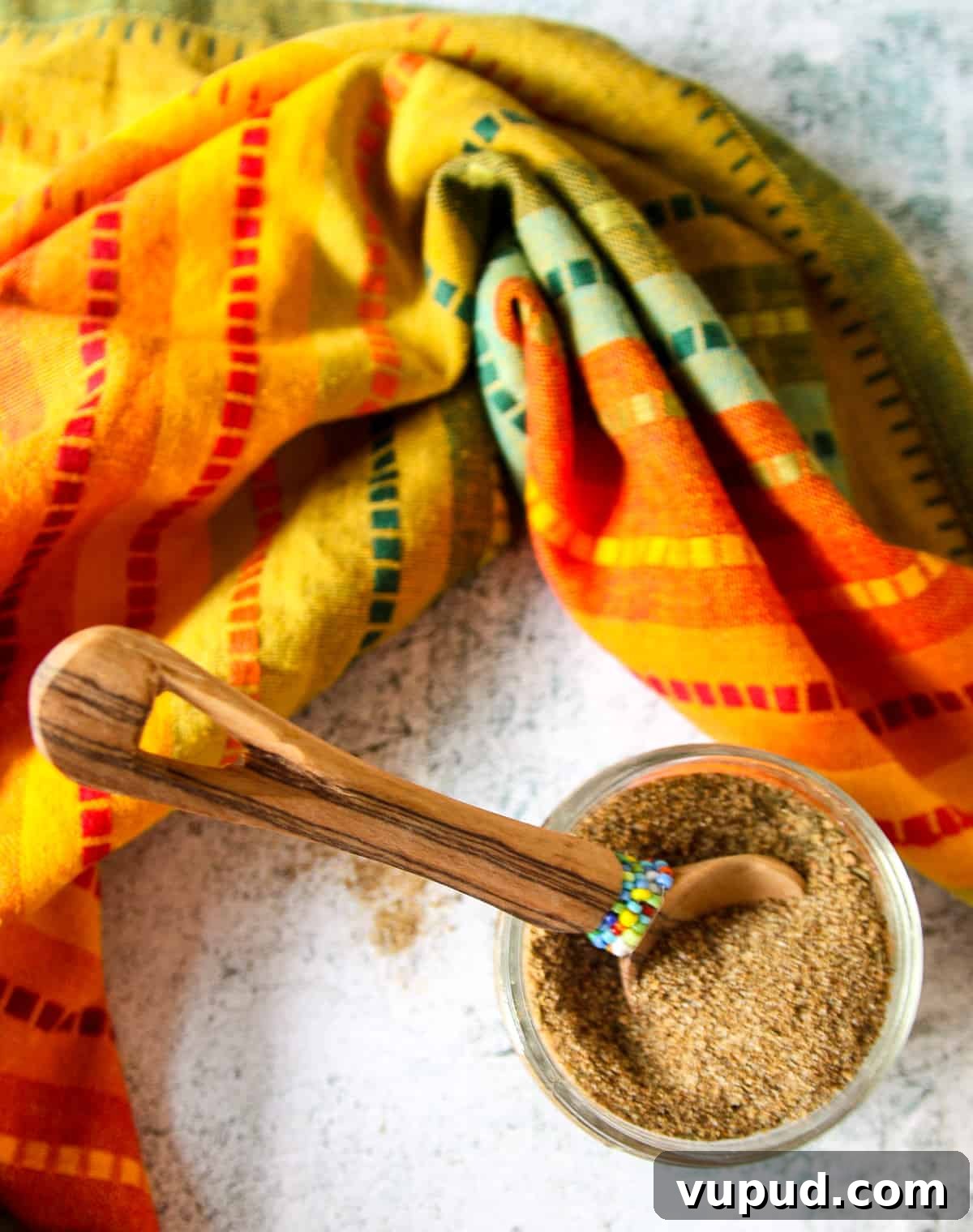 A jar of Jamaican jerk seasoning with a small wooden spoon in it.