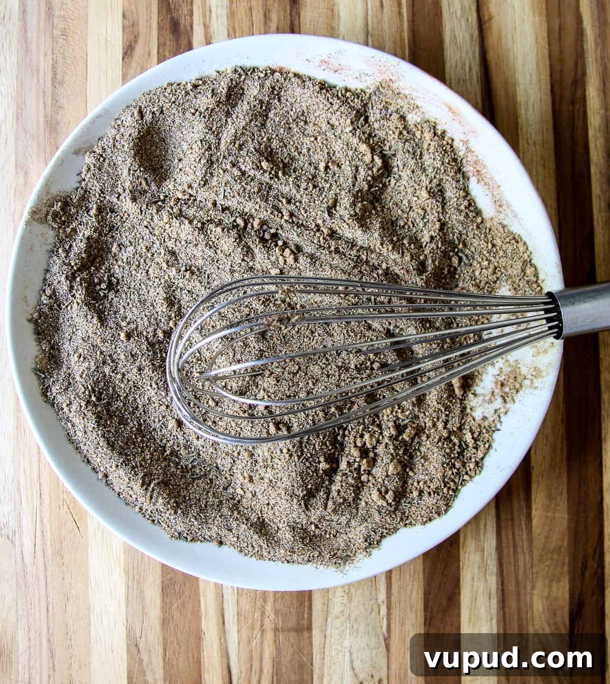 The spices being whisked together in a white bowl.