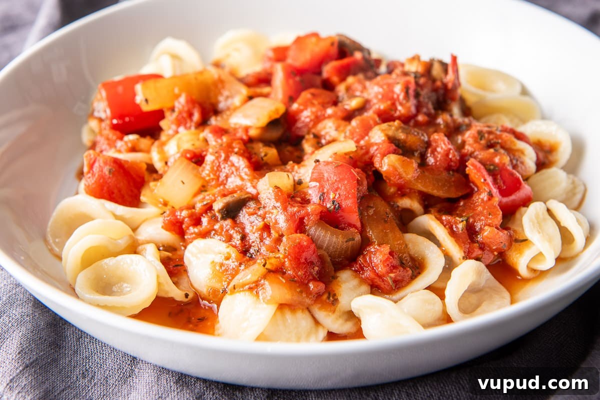 Rich Tomato Gravy Recipe: Savory Red Sauce for Pasta & Biscuits 3 A shallow white bowl filled with pasta and gravy on a grey napkin