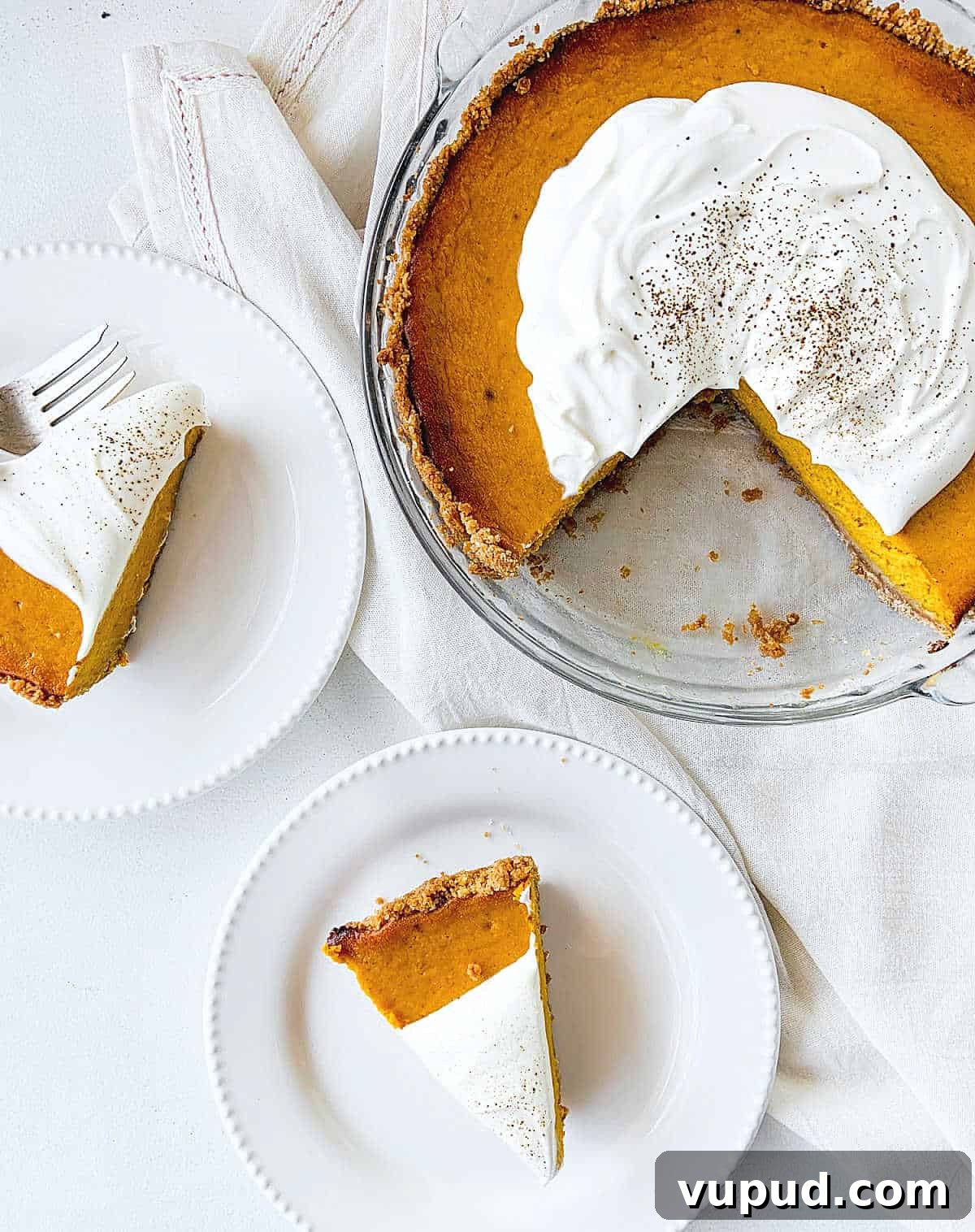 Pumpkin Pie with Graham Cracker Crust Recipe for Fall Baking 13 View from above of pumpkin pie in a glass plate, slices in white plates on a white surface.