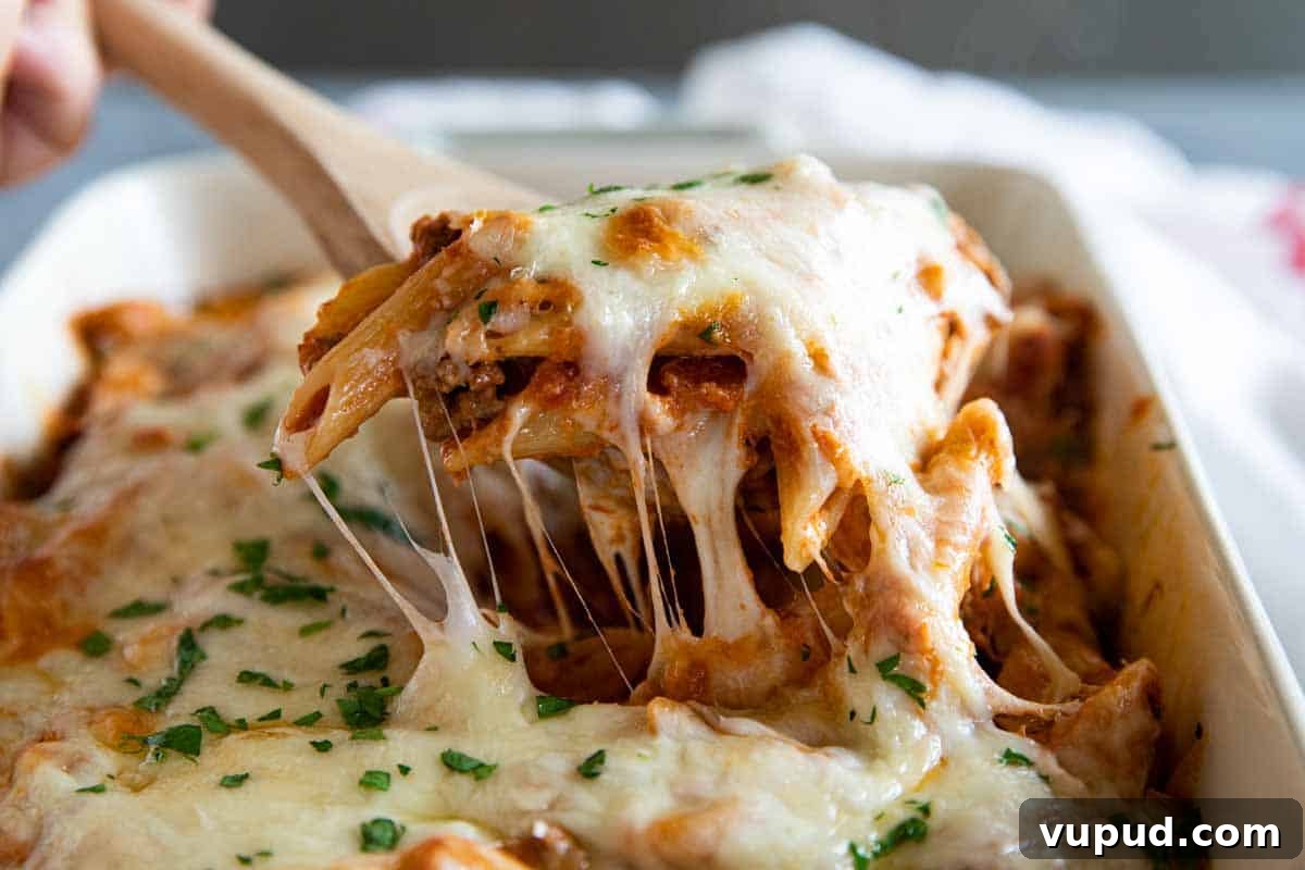 Penne Pasta Bake taking a scoop of penne pasta bake out of casserole dish