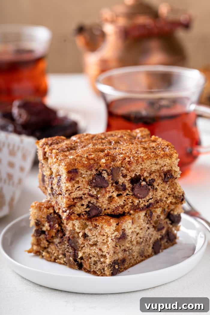 Decadent Date Cake Recipe with Warm Spices 2 Two slices of date cake stacked on a white plate.
