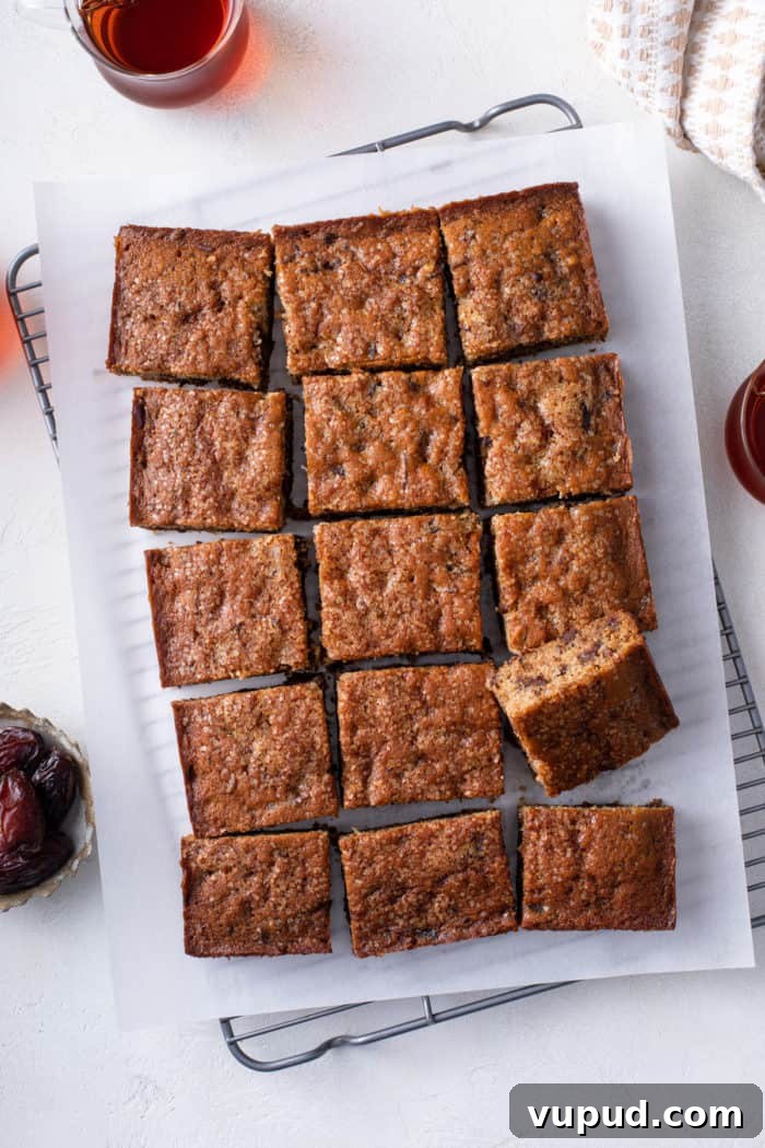 Decadent Date Cake Recipe with Warm Spices 3 Overhead view of sliced date cake on a parchment-lined wire cooling rack.
