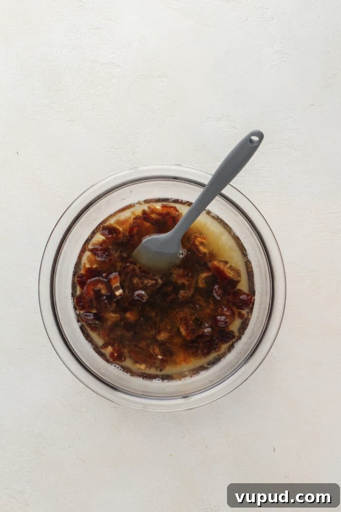 Decadent Date Cake Recipe with Warm Spices 4 Dates soaked in water and baking soda in a glass mixing bowl.