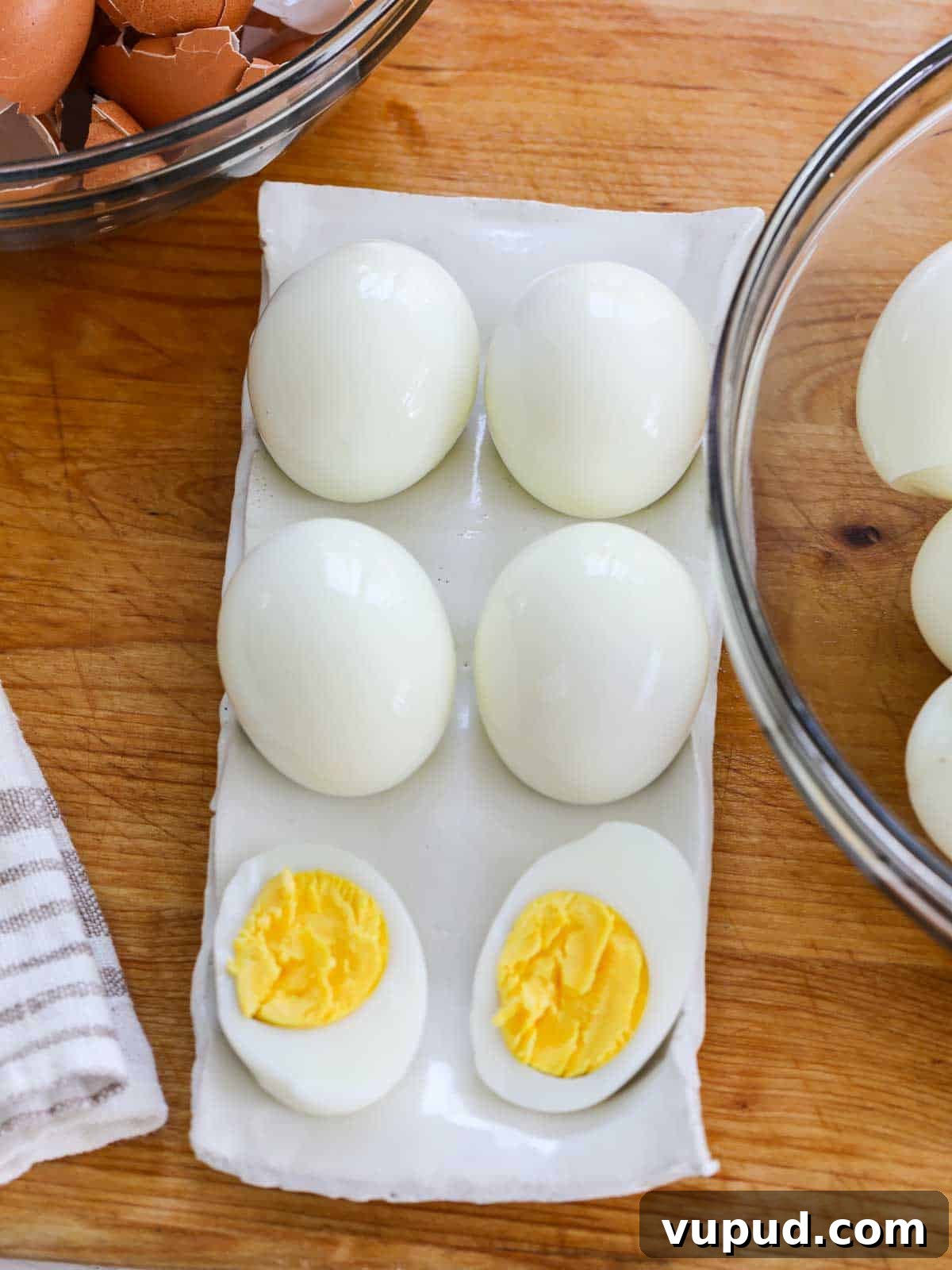 Festive Christmas Deviled Eggs Recipe for Holiday Parties 6 Looking down on a white ceramic egg dish with hard boiled eggs and one sliced open to reveal the yolk
