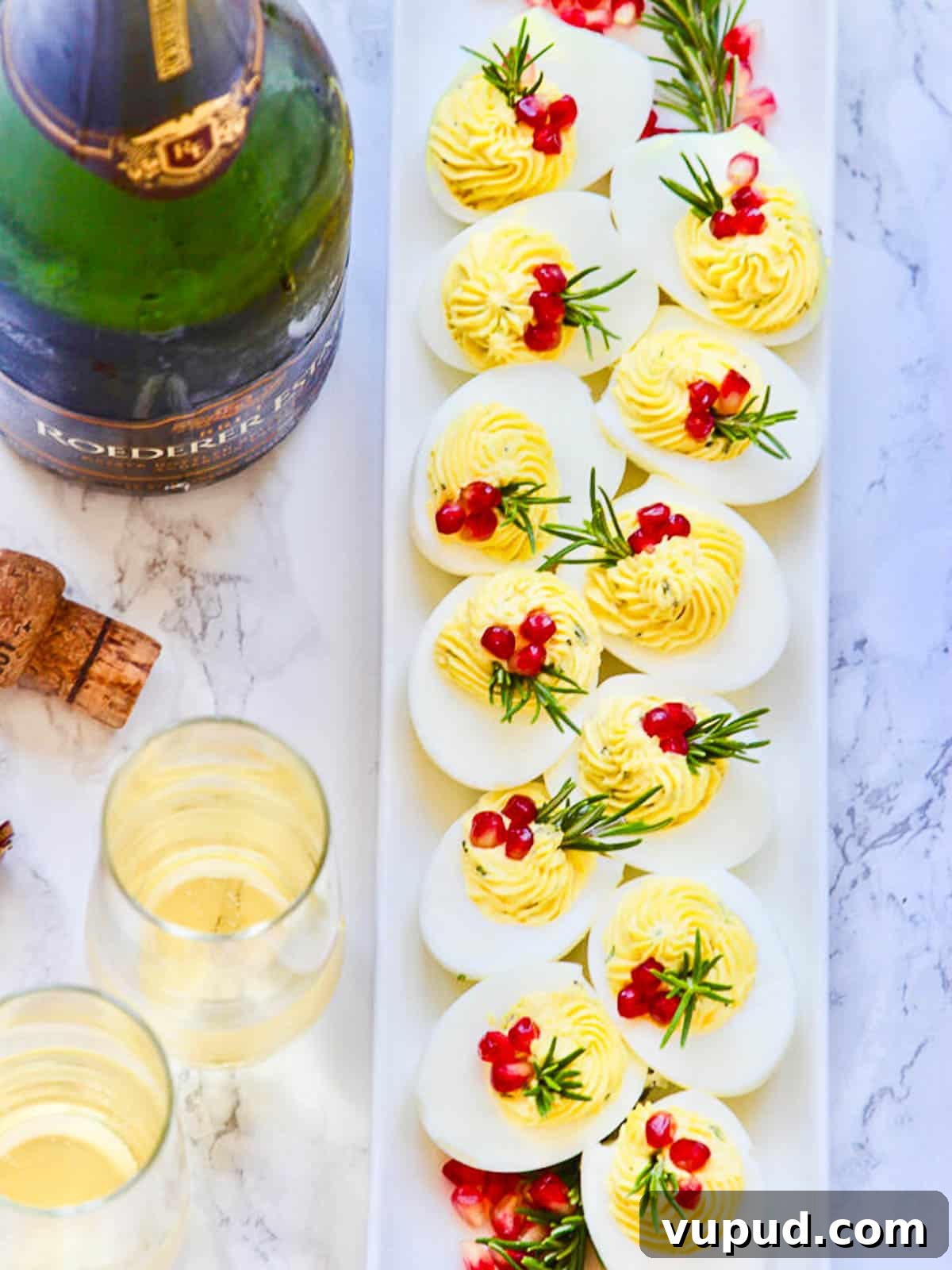 Festive Christmas Deviled Eggs Recipe for Holiday Parties 7 Holiday Christmas deviled eggs with two glasses of Champagne and a cork on a kitchen counter.