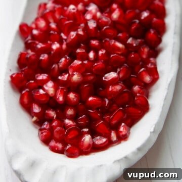 Festive Christmas Deviled Eggs Recipe for Holiday Parties 8 A white ceramic dish with pomegranate seeds ready to use in a recipe.