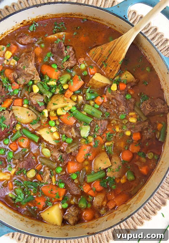 overhead shot of mulligan stew in a stock pot with a wooden spoon.