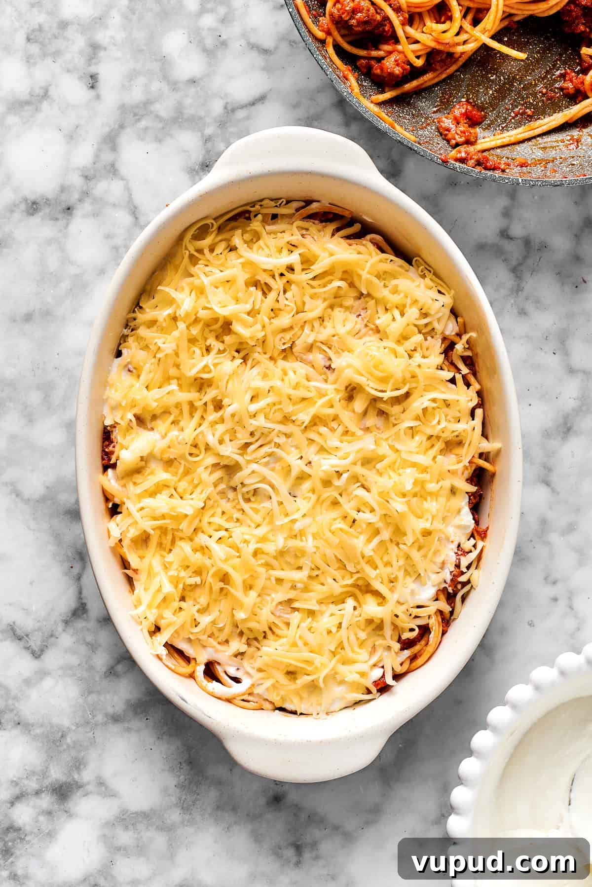 Add cheese & bake. Adding a layer of shredded cheese on top of spaghetti in a 9x13 dish.