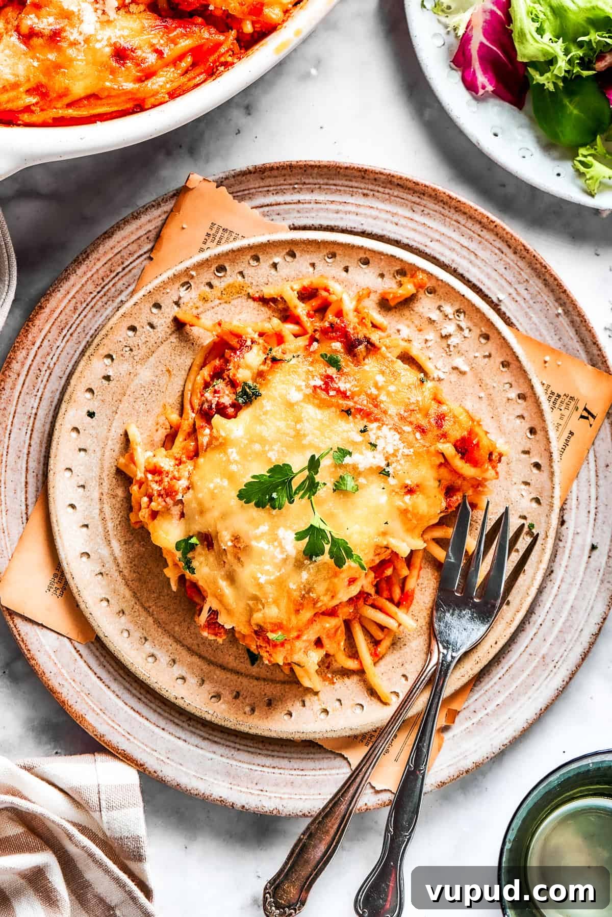 Million dollar spaghetti is an easy spaghetti casserole made from pasta tossed in homemade meat sauce and baked with layers of melty cheese. A serving of million dollar spaghetti served on a plate with forks.