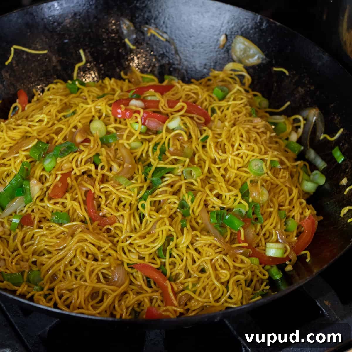 Vegetable Chow Mein Recipe: Flavorful Stir-Fry with Crunchy Veggies 7 Noodles in a wok with peppers and green onions.