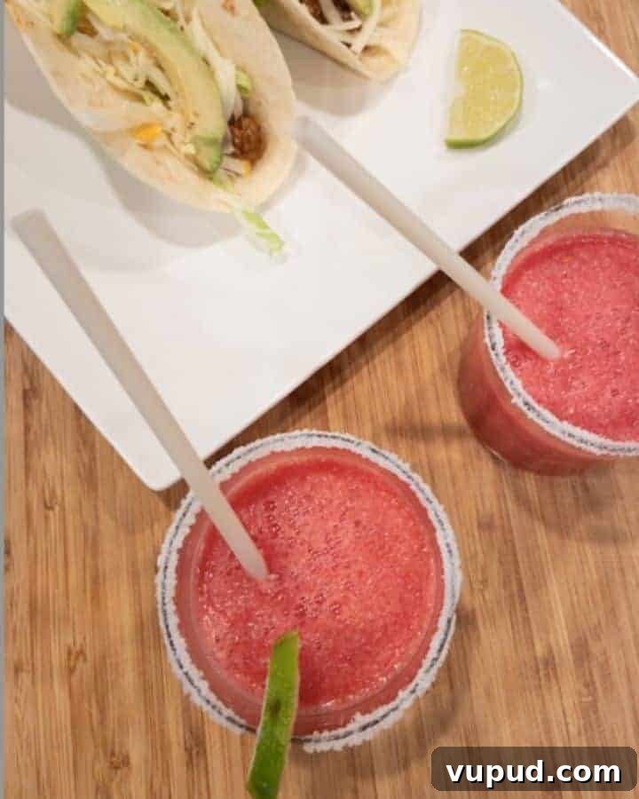 Frozen Watermelon Margarita Recipe for Summer Parties 2 Two frozen watermelon margaritas with salt and lime garnish with tacos on white plate