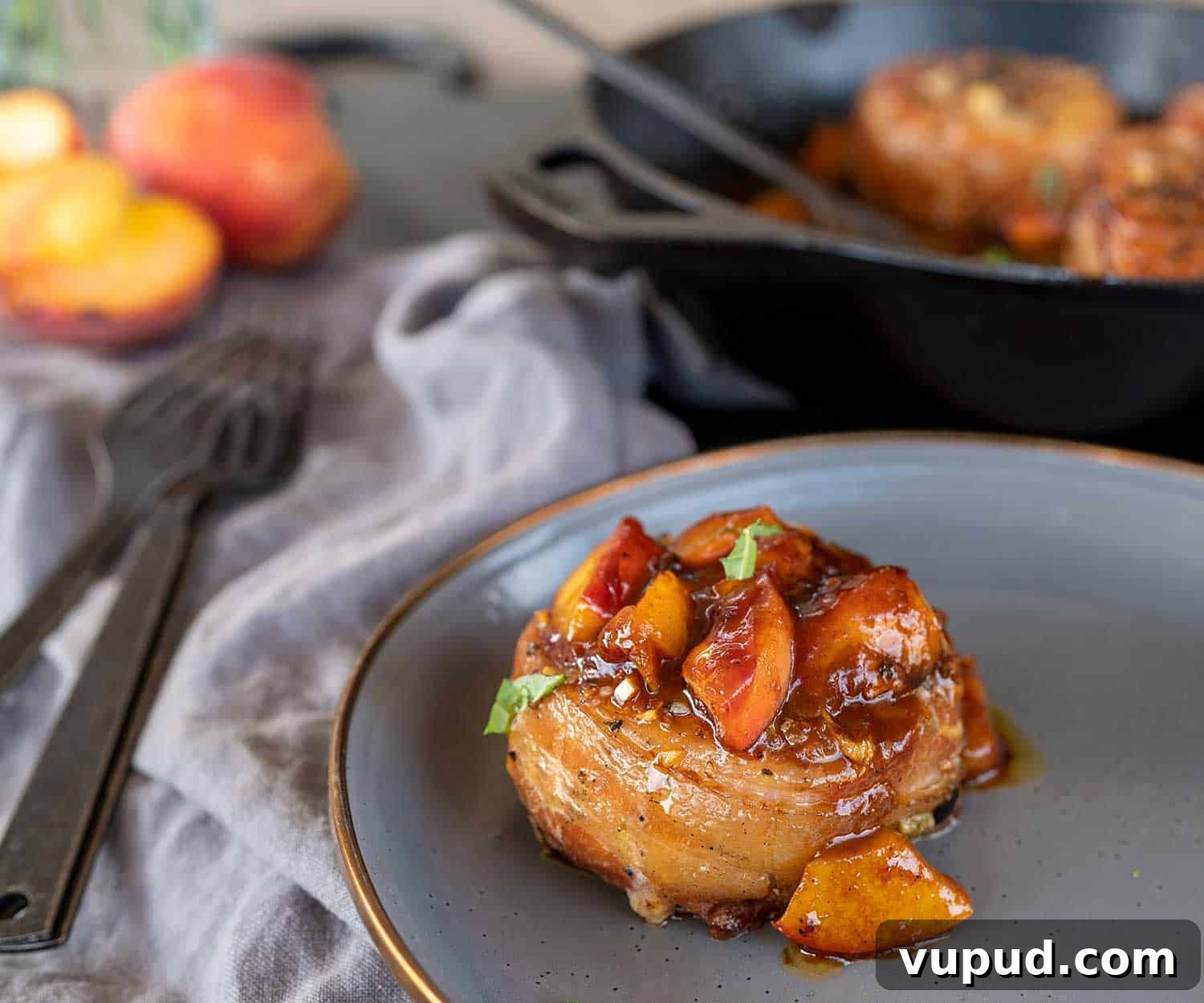 Whiskey-Peach Glazed Bacon-Wrapped Pork Loin Filets 2 overhead shot of bacon-wrapped pork loin filet on plate by pan of filets.